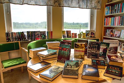 Biblioteksrum med böcker på bord och i bokhyllor.
