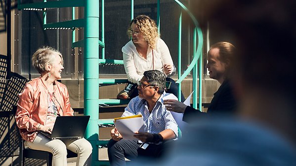 En grupp människor sitter och samtalar i en trappa