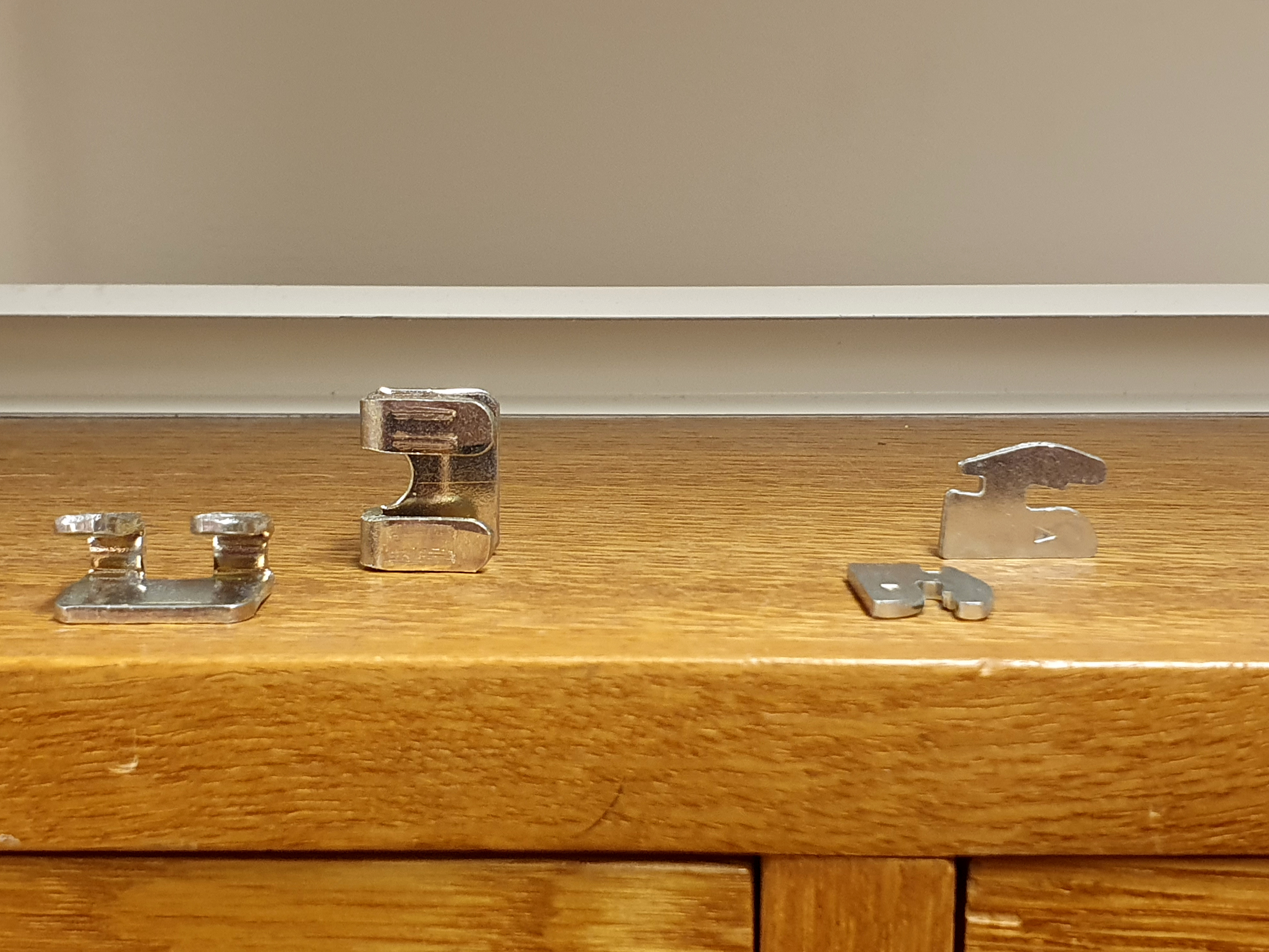 Foto av några olika typer av hyllbärare i metall som ligger ovanpå en trähylla.