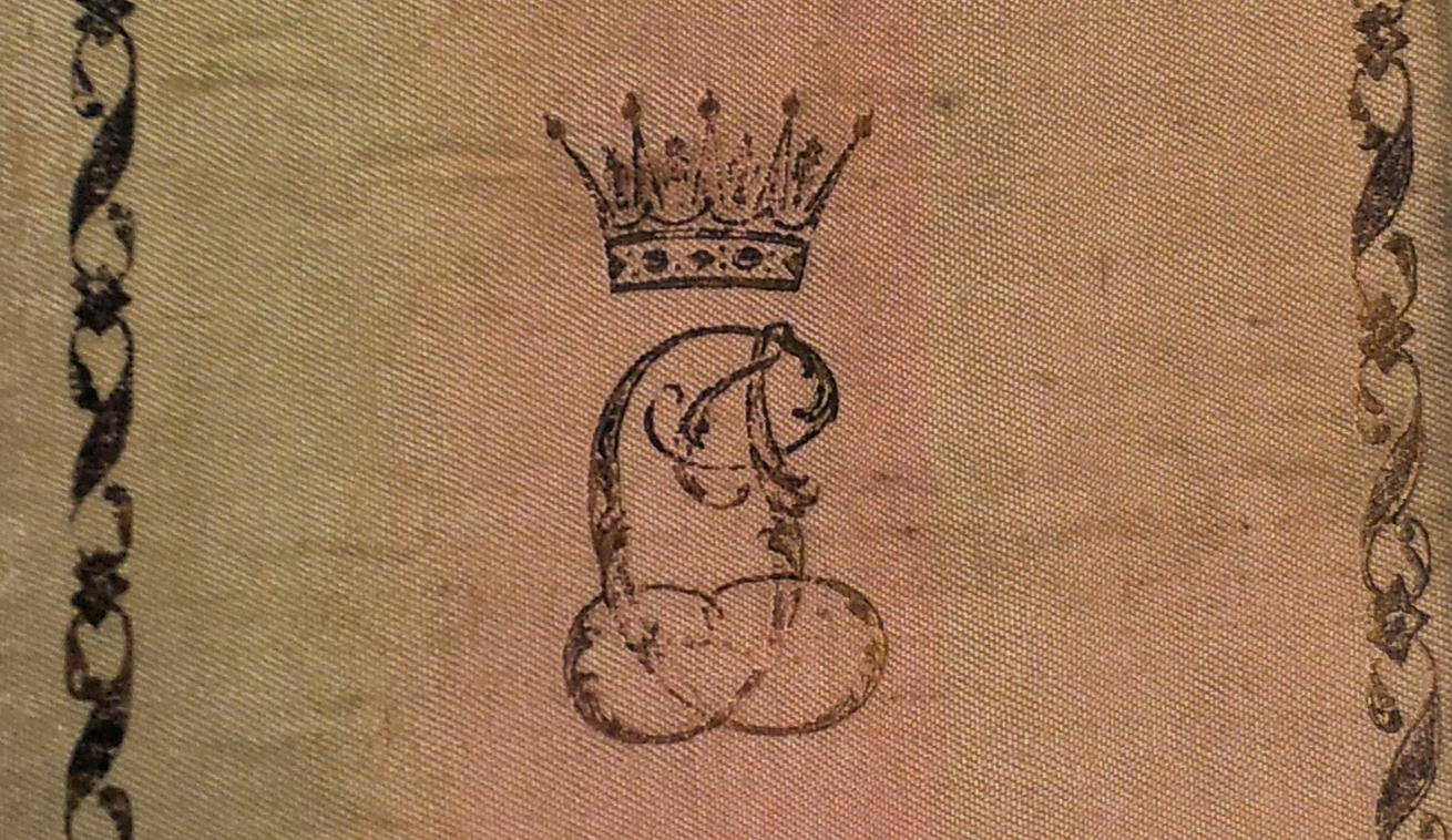 Rosa textilband med Karl XIV Johans pärmexlibris. Foto: KB