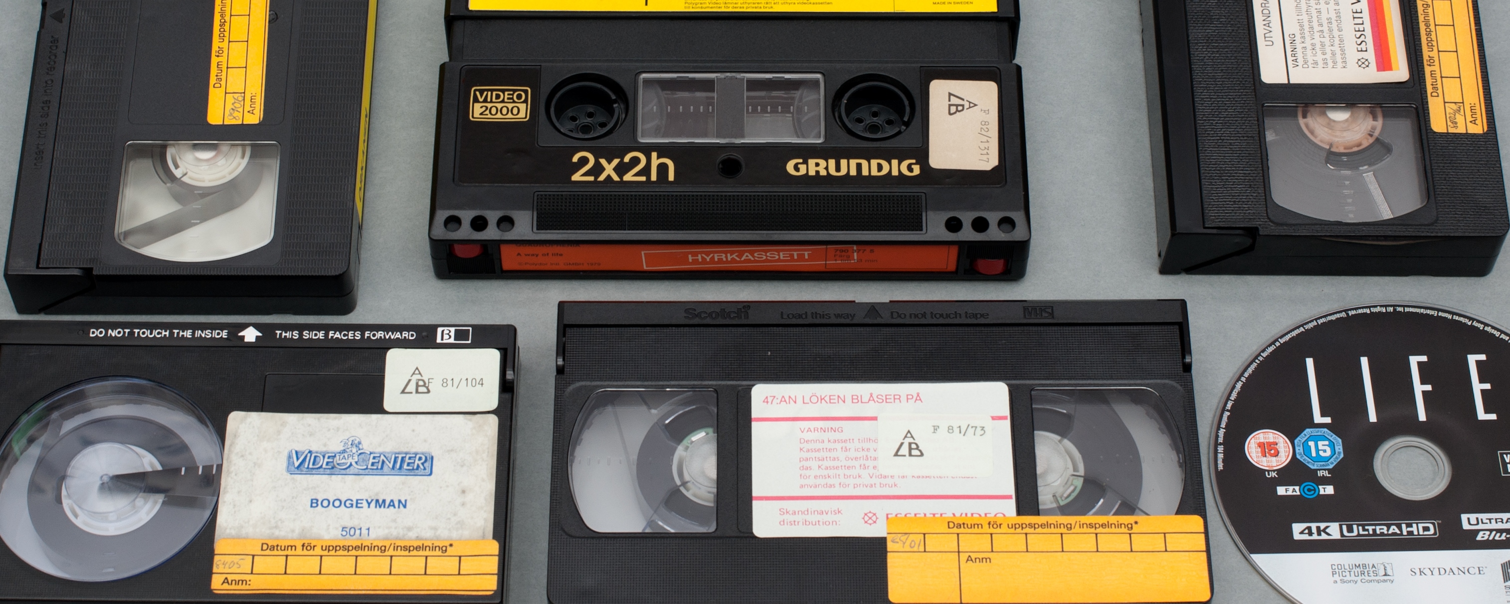 Videokassetter (VHS-band) och en DVD-skiva på ett bord.