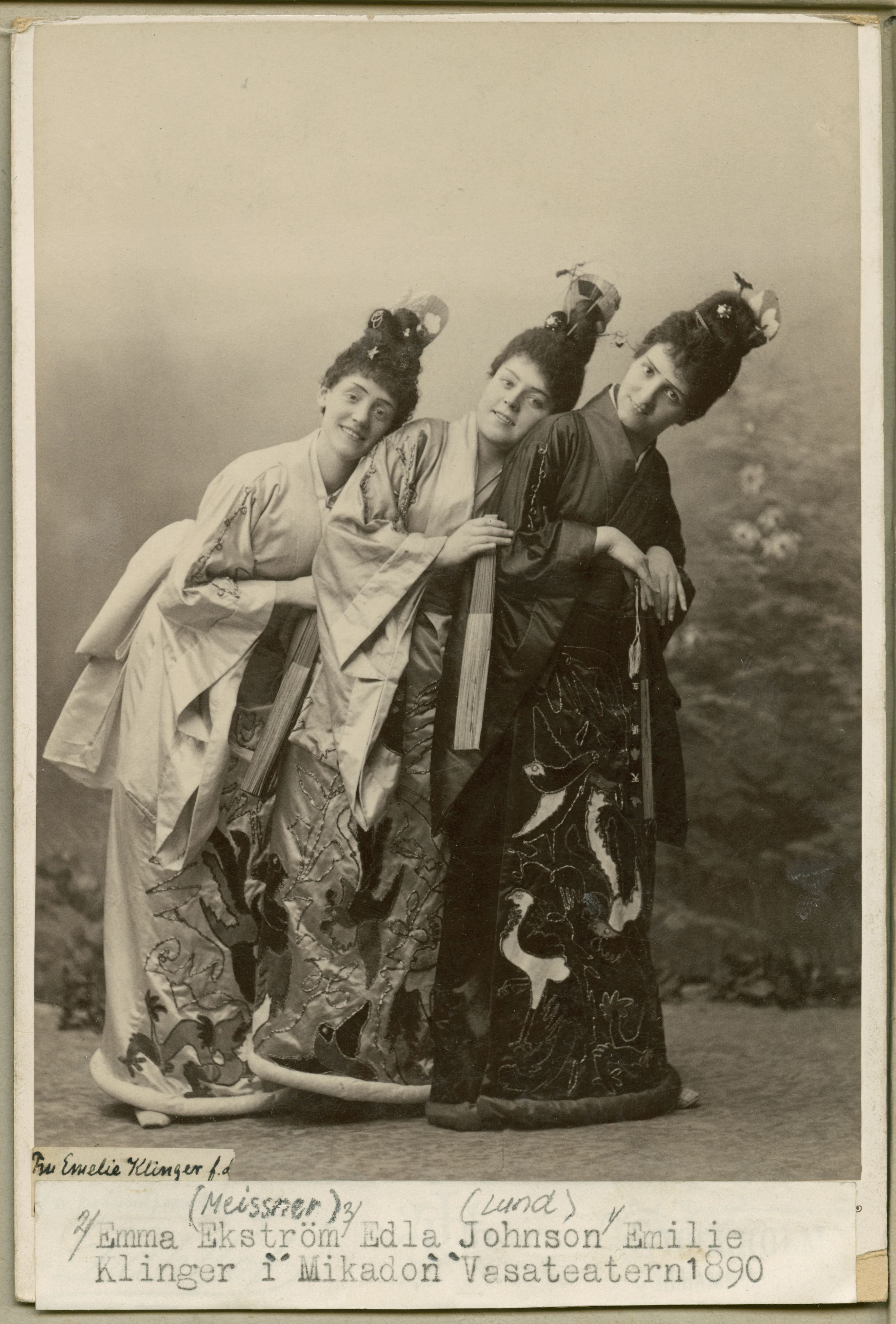 Svartvitt foto av tre kvinnor i traditionella japanska kläder. De ler mot kameran 