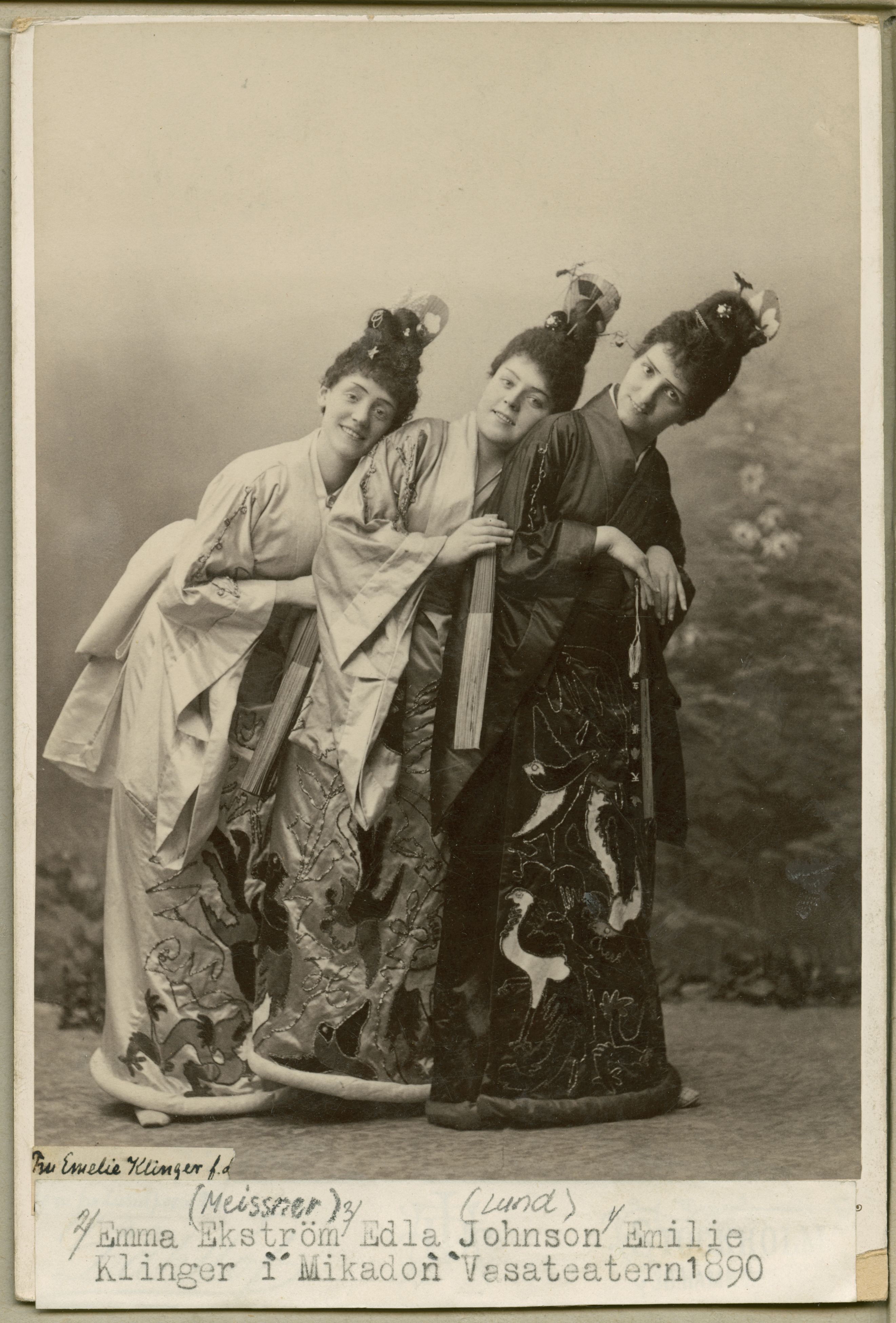 Svartvitt foto av tre kvinnor i traditionella japanska kläder. De ler mot kameran