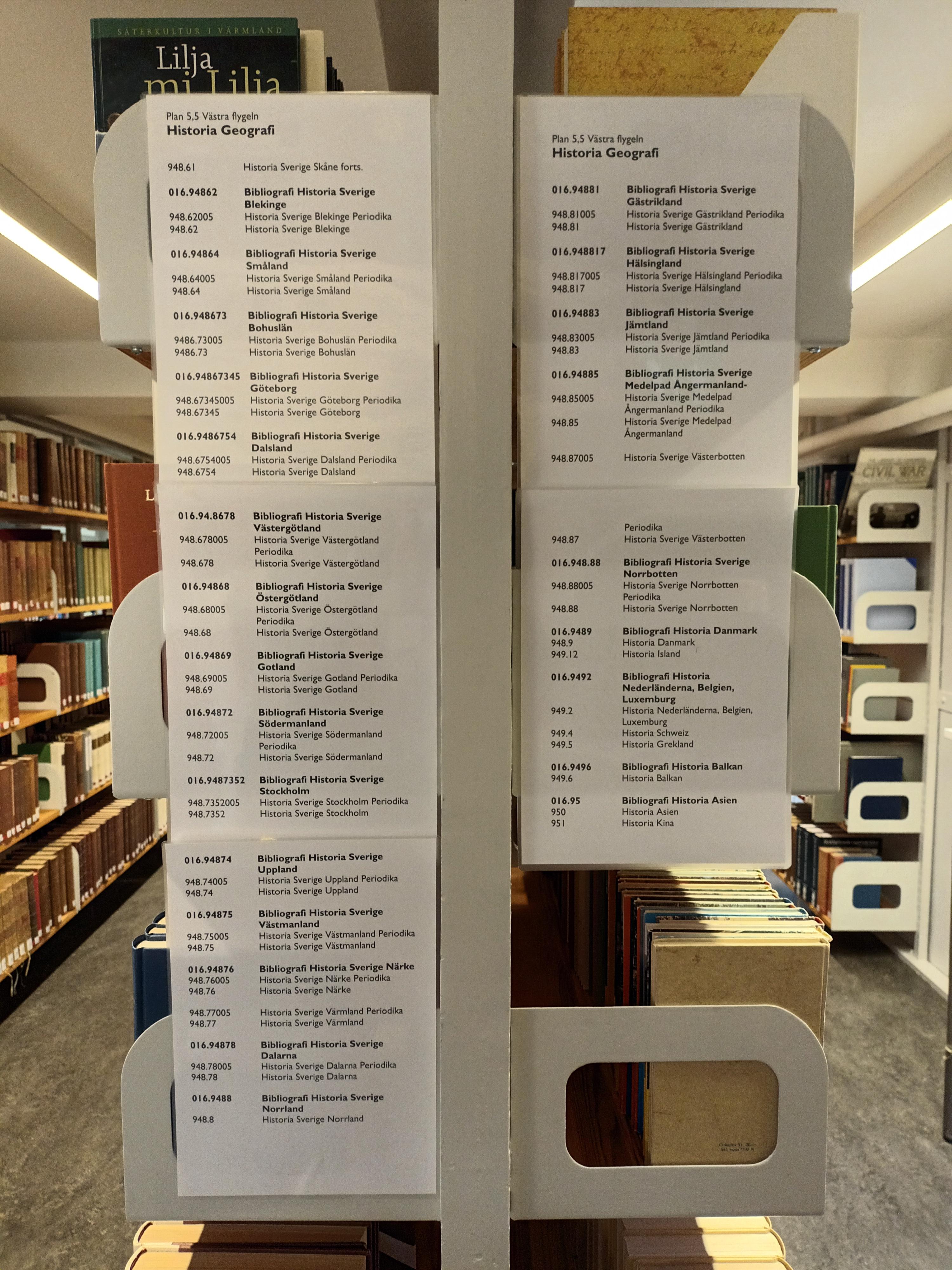 Hyllgavel i KB:s referensbibliotek. Informationsskyltar om uppställning av referensböcker i historia och geografi enligt Dewey decimalklassifikation.
