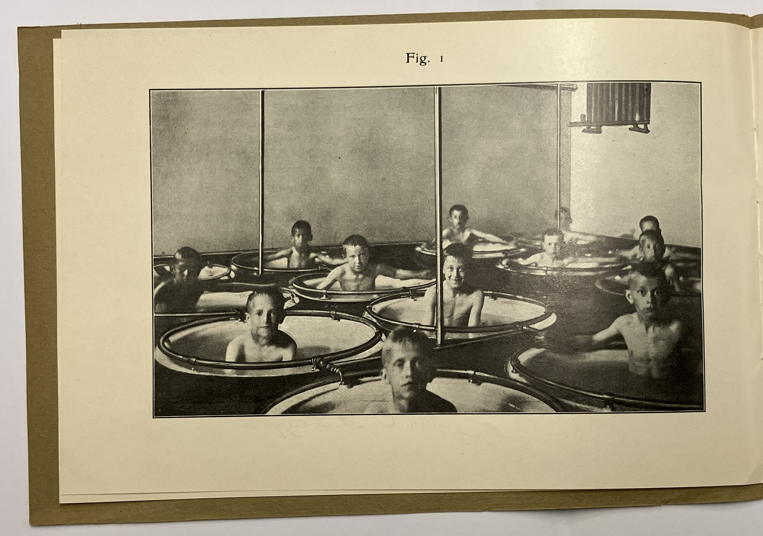 En fotografi från en katalog för "skolbad" som föreställer pojkar som sitter i enskilda egna badkar på en badanstalt alt. skola.