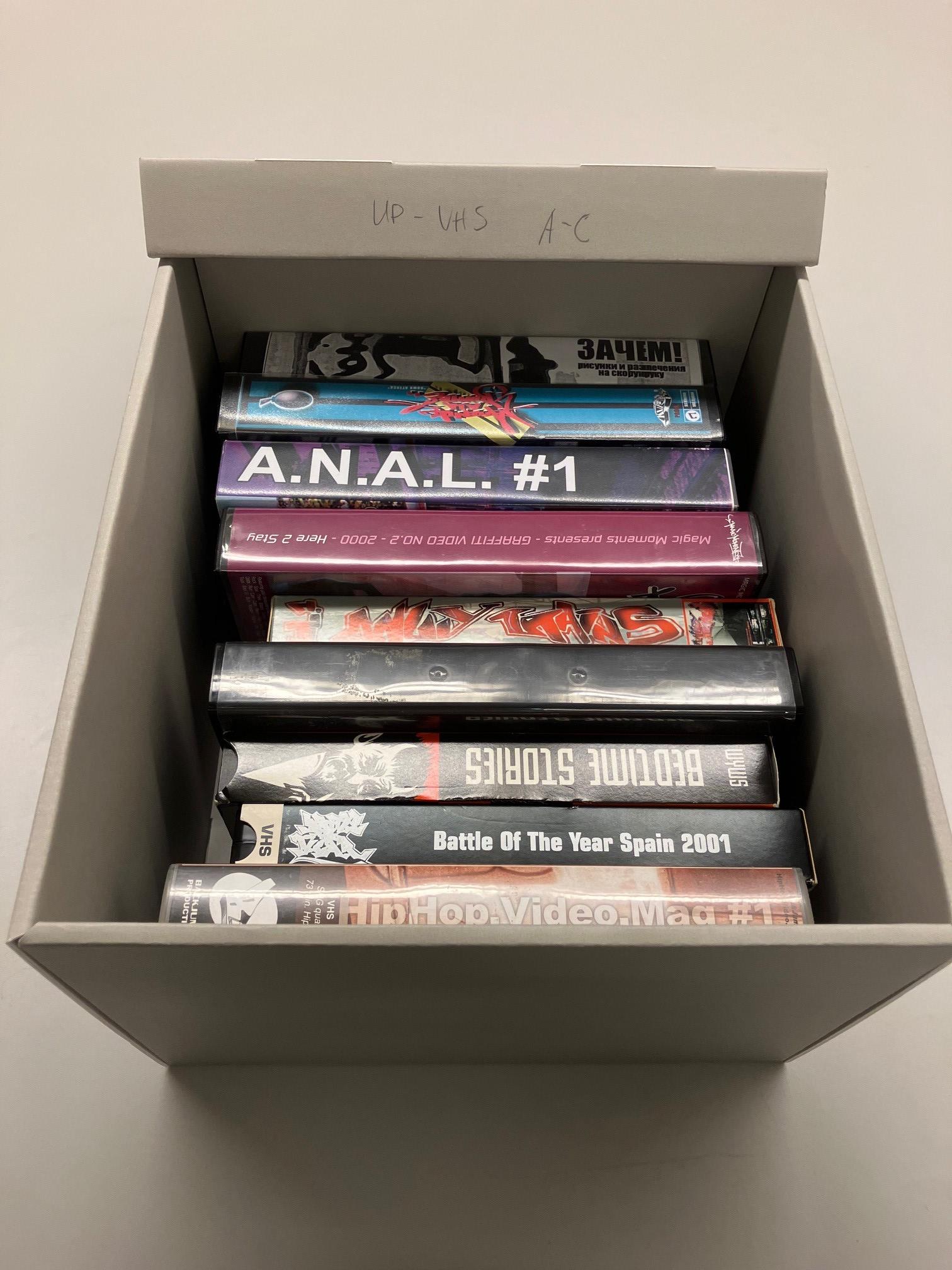 Färgfoto av öppnad arkivbox med ryggtitlar på vhs-band.