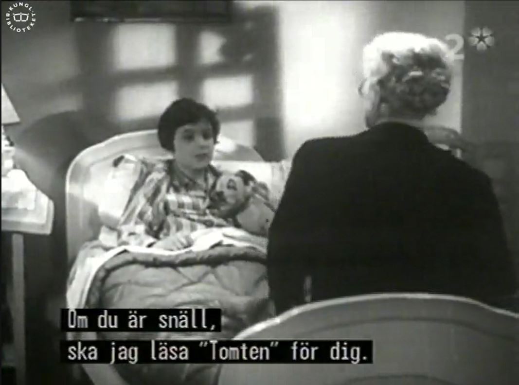 Svartvit bild från tv-sändning med ett barn som ligger i sängen. Framför barnet syns ryggen på en äldre kvinna i hårknut sittandes på sängkanten.