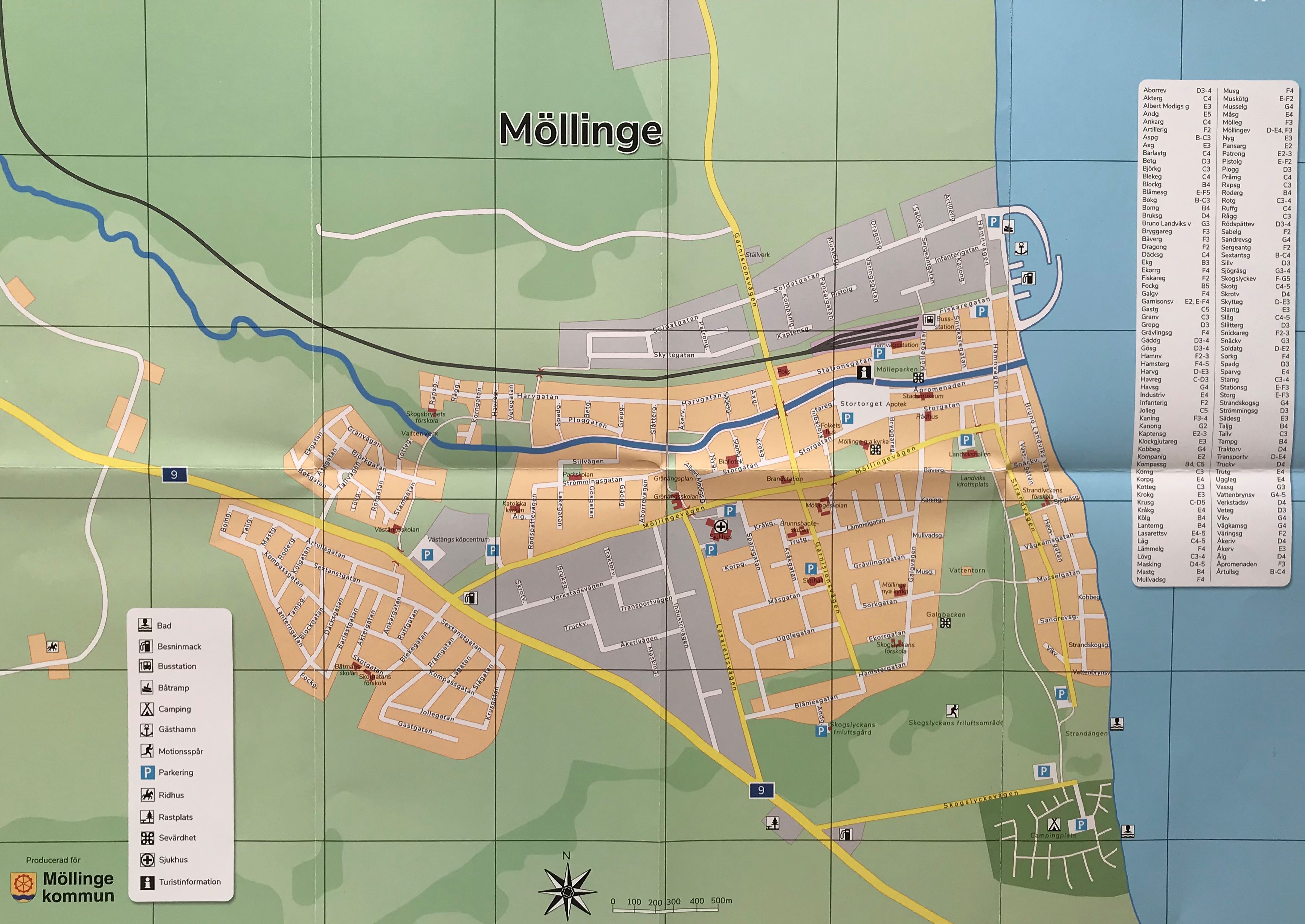 Kommunkarta över Möllinge, där bebyggda områden illustreras av grå och orange ytor. Områdena utanför bebyggelsen är gröna. En å, i form av ett blått streck, går genom samhället och ut till havet på öster sida. Källa. KB