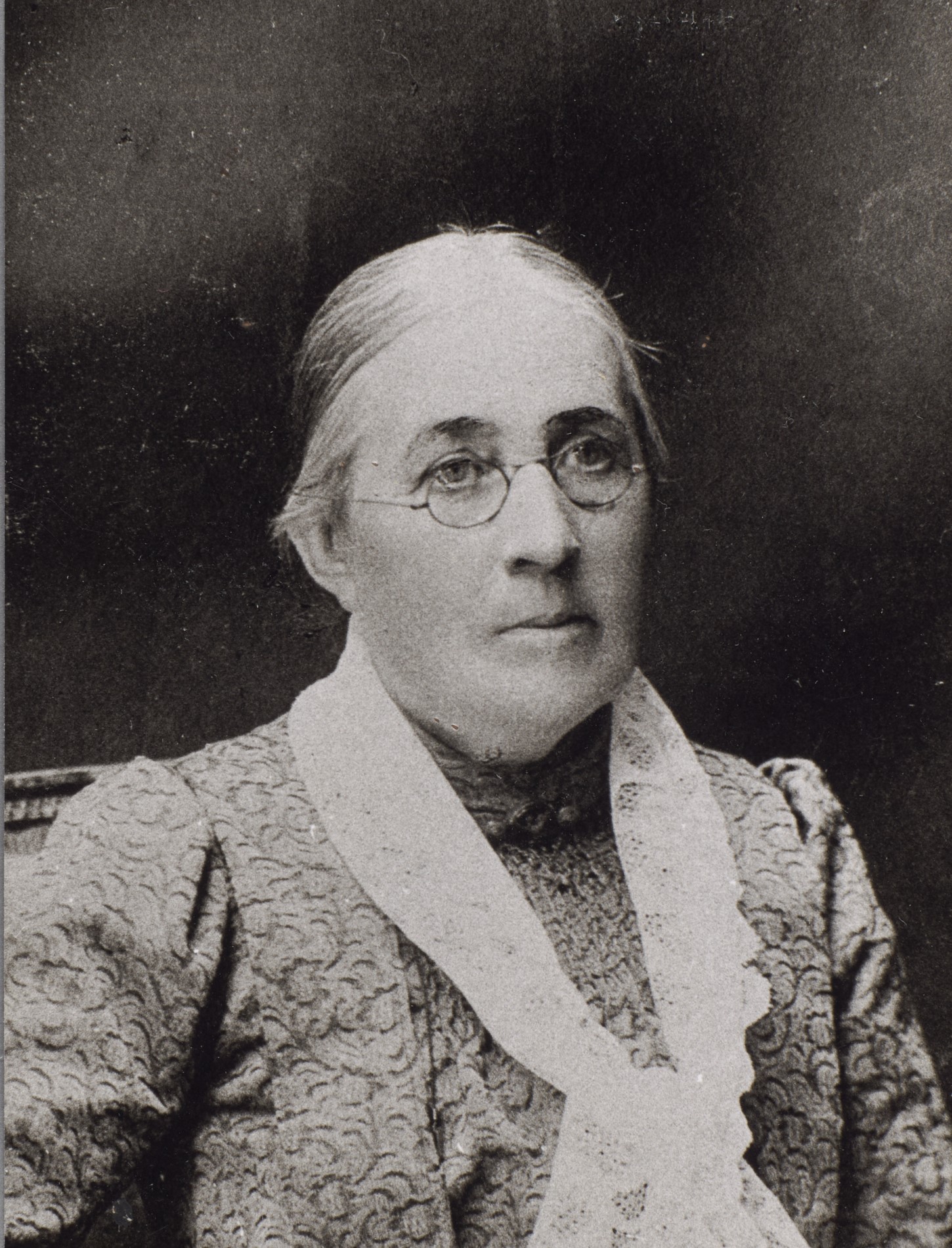 Fotografi av en äldre kvinna med glasögon och håret i knut