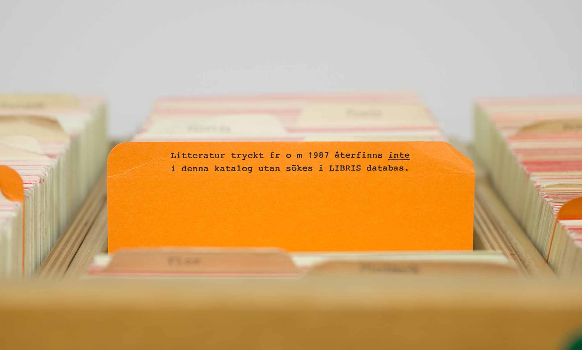 Ett orange katalogkort i en trälåda.