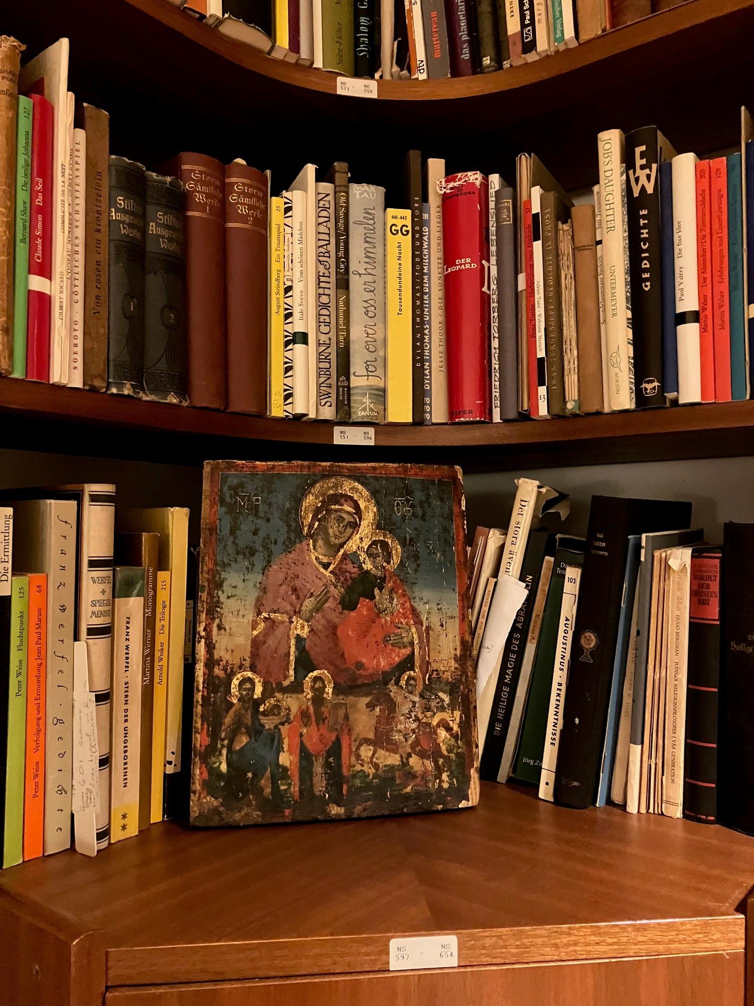 Färgfoto som visar del av en bokhylla med böcker och en ikon med Maria och Jesusbarnet.