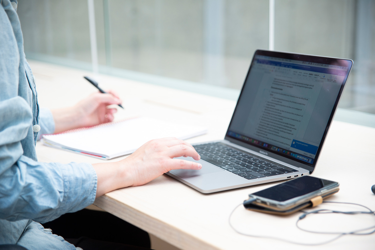 Person sitting by laptop, writing.