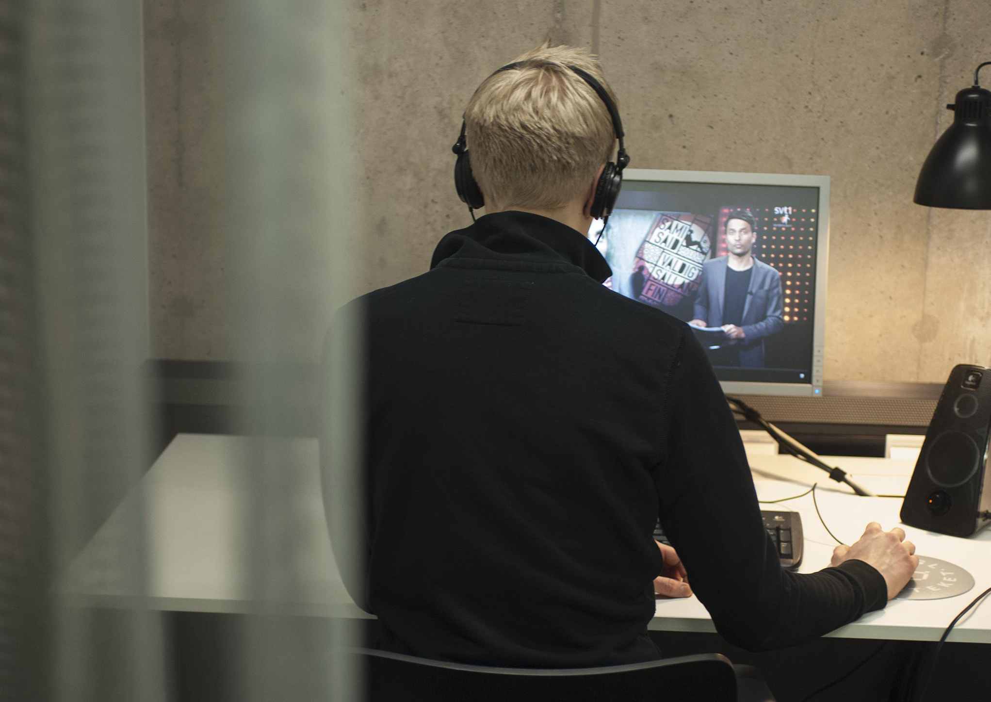 En person sitter vid en dator med hörlurar och tittar på ett svt-program i tjänsten Svensk mediedatabas.