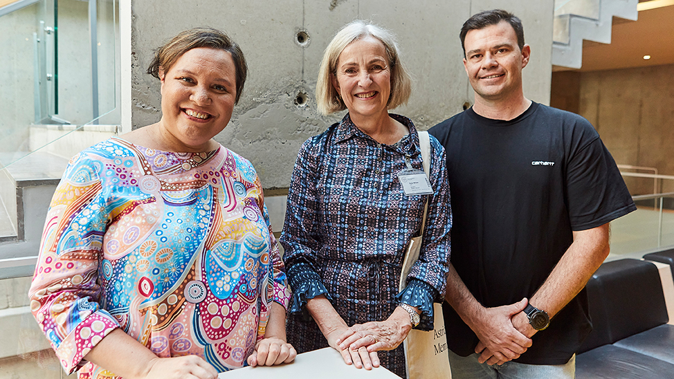 Tre personer ler och tittar in i kameran.