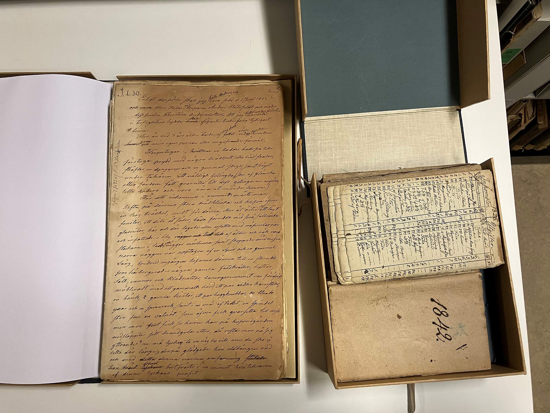 Till vänster är en kapsel med en handskrift, Anders Lundquists livsberättelse med signum Il 30. Till höger är en kapsel med anteckningsböcker, också del av Anders Lundquists arkiv, med signum Il31.