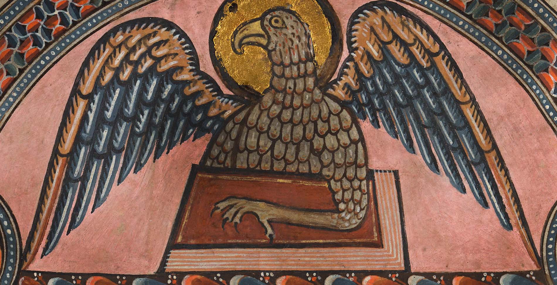 En detaljbild av en örn med färgglada vingar med ena klon liggande över en röd bok.