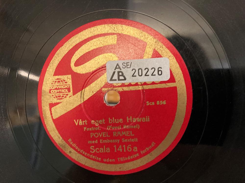 Närbild av en röd etikett med text i guld omgiven av svart vinyl.