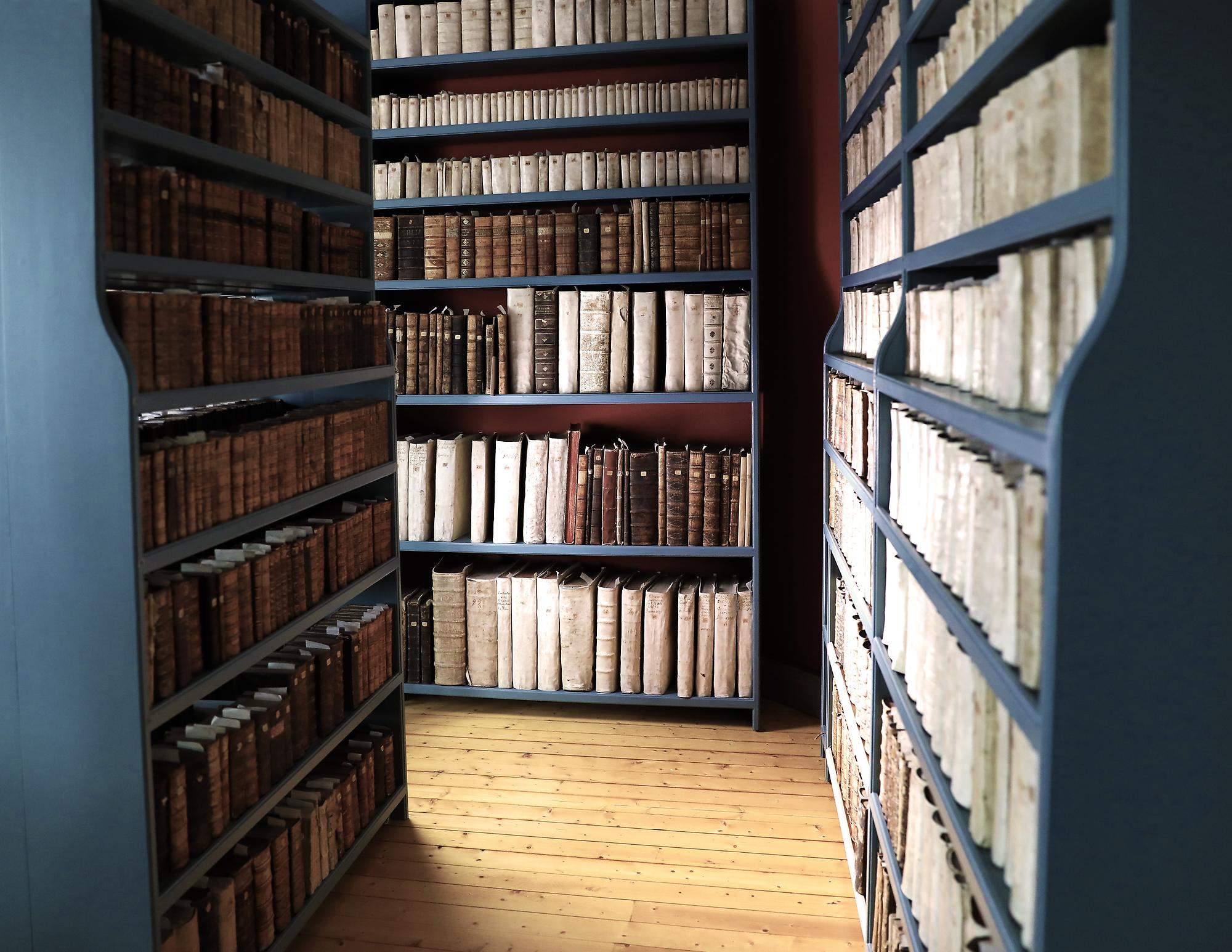 Interiör som visar blå bokhyllor med äldre böcker.