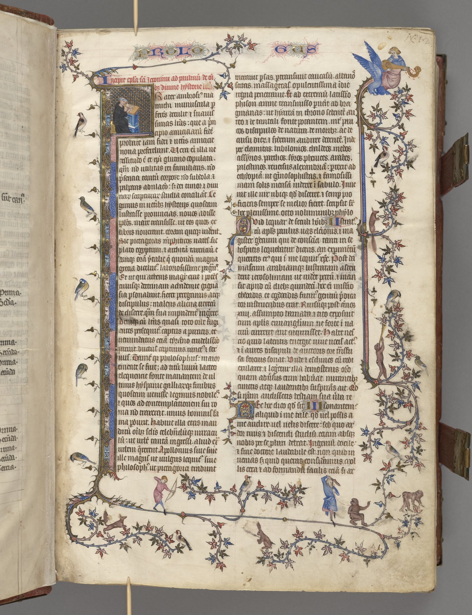 Färgfoto av blad med text i två spalter omgärdad av sirlig blomstergirlang. Bland blommorna syns bland annat en person med pilbåge, fåglar och apor.