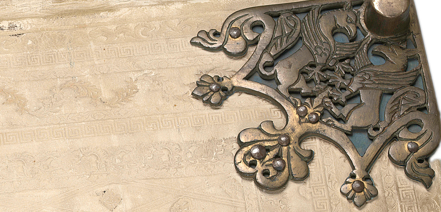 Close-up of one of the cornes of a white book with metal ornaments.