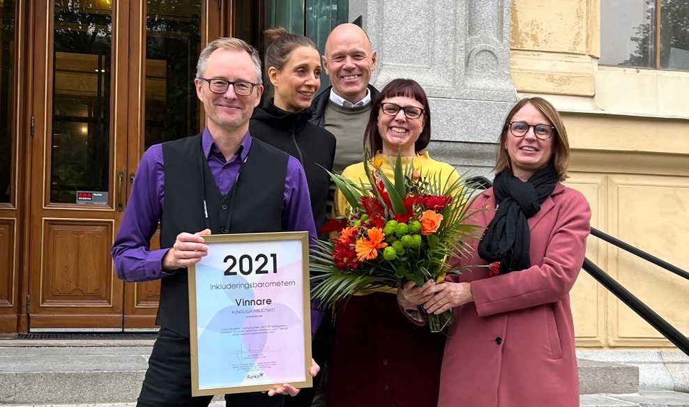 Fyra glada personer med blombukett och diplom står på en trappa.