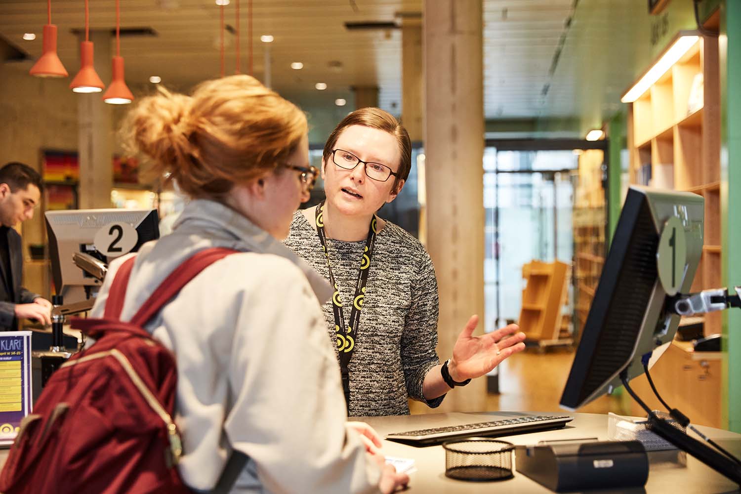 En kvinna på bibliotek visar en annan kvinna något på en skärm.