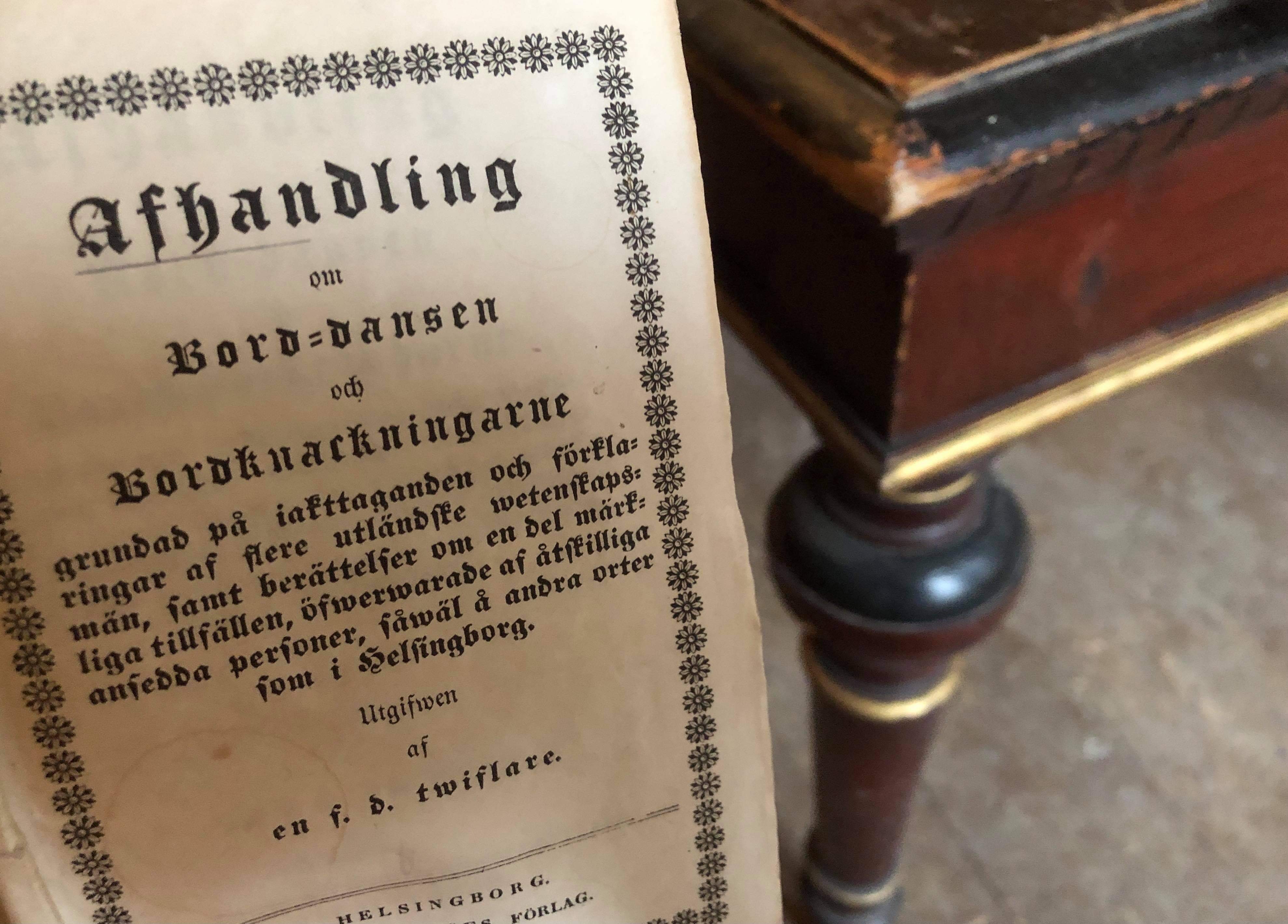 Ett foto på skriften Bord-dansen med ett äldre bord i bakgrunden.