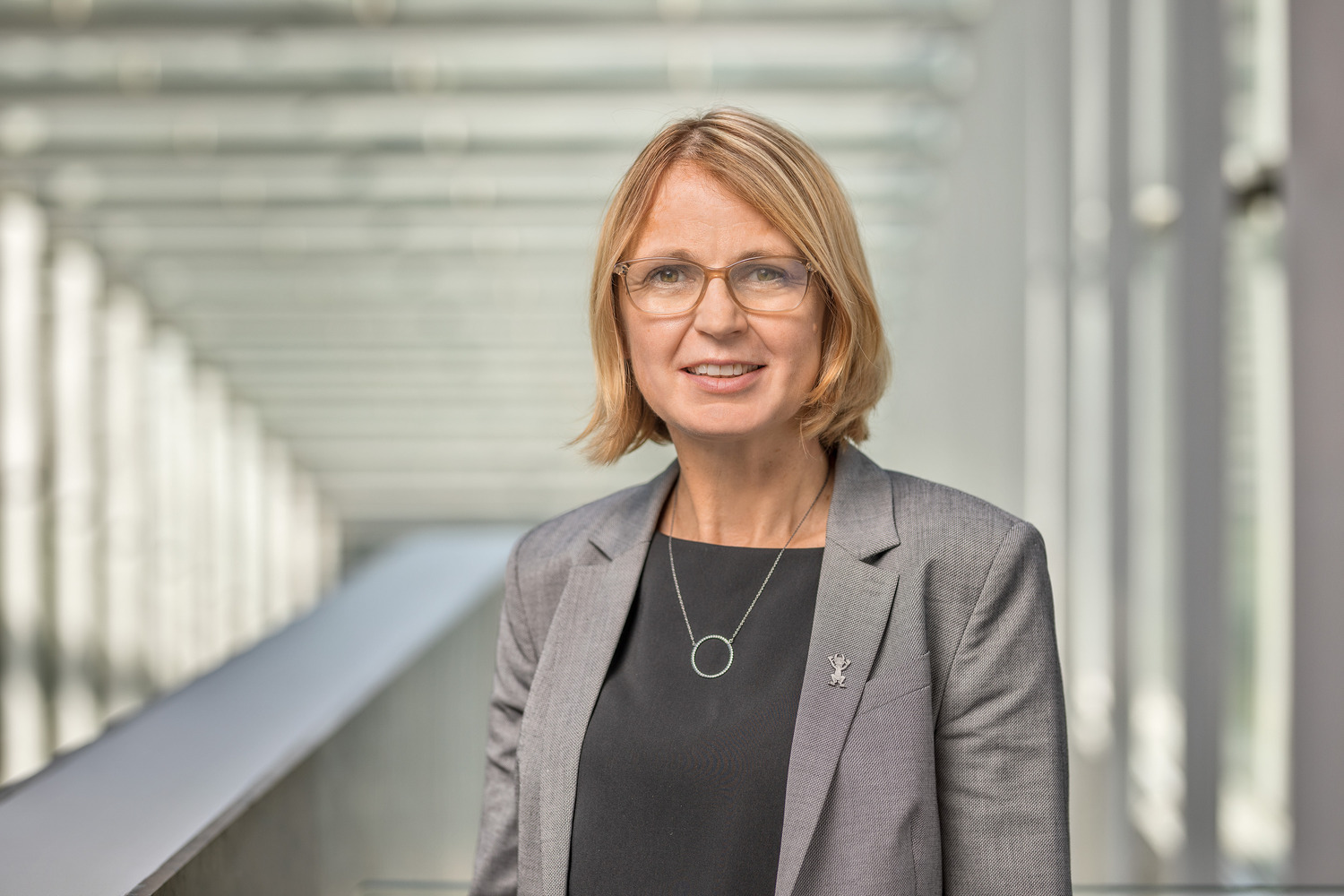 Kvinna i blont hår och grå kavaj.