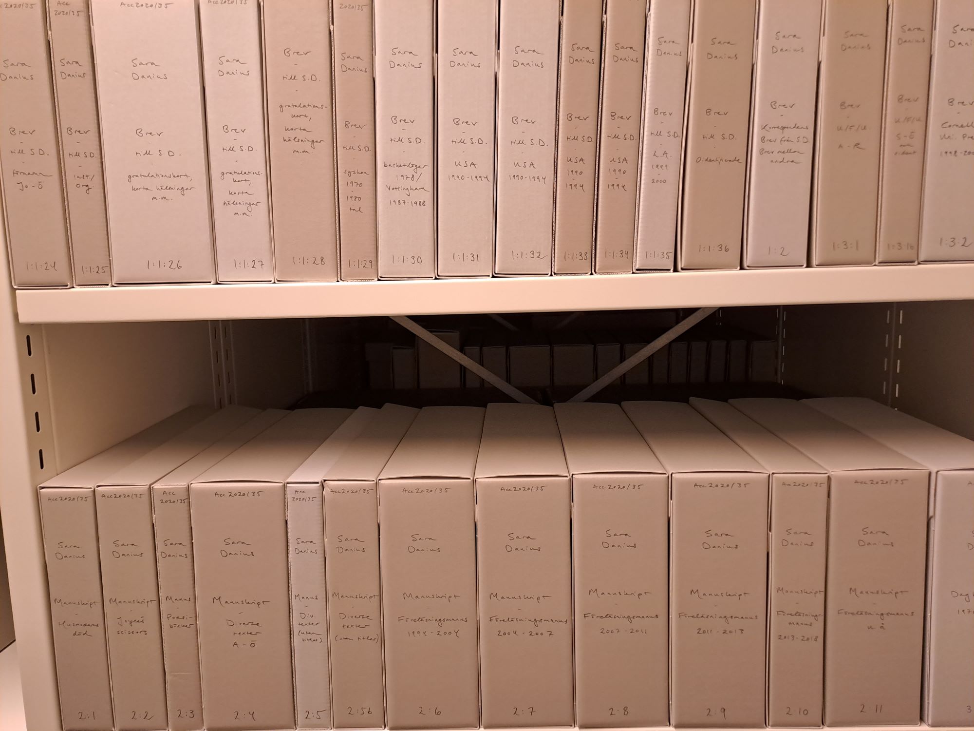 Två hyllplan fulla med grå arkivkapslar.
