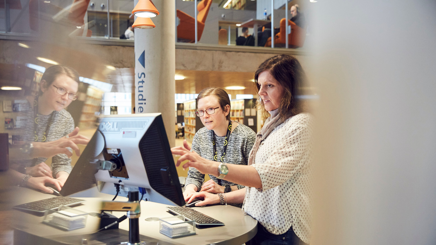Biblioteksmedarbetare hjälper användare vid informationsdisk.