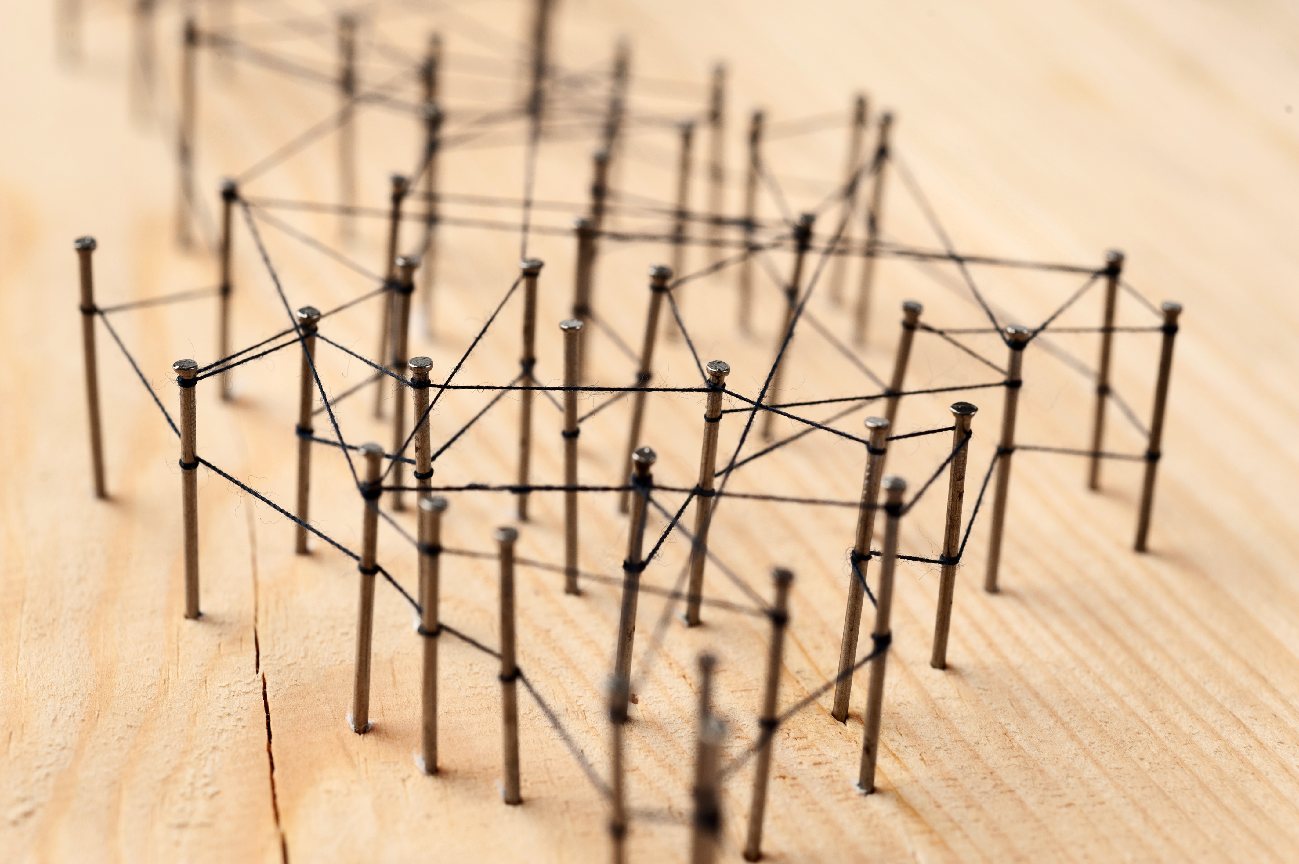 Nails in wood connected by strings.