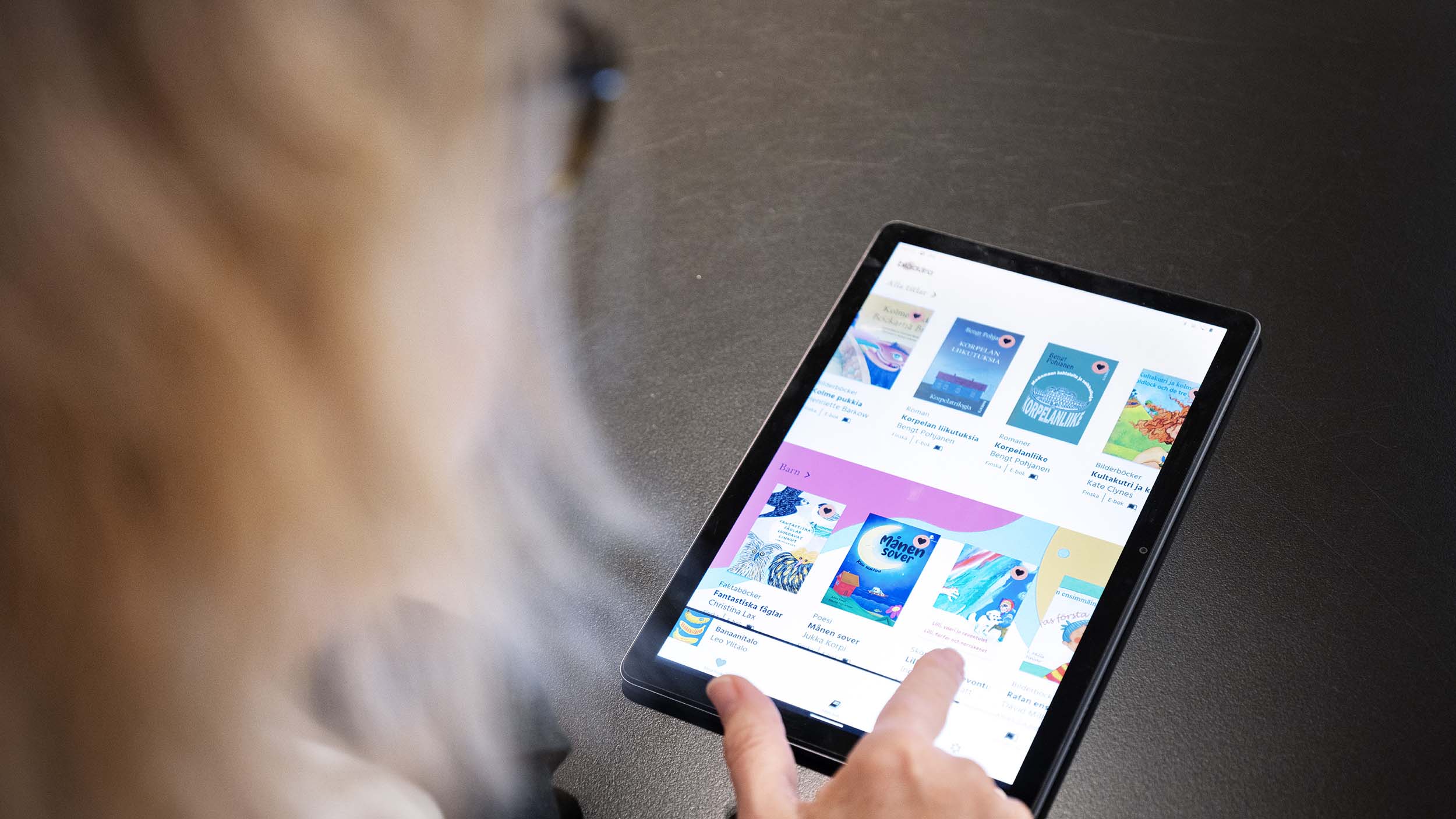 En kvinna fotograferad bakifrån tittar på appen Bläddra i en Ipad