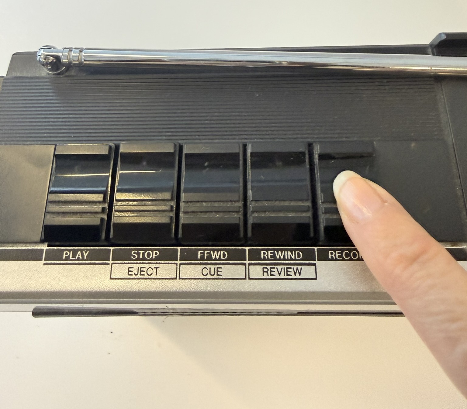 Knappar på kassettbandspelare. Ett finger trycker på record.