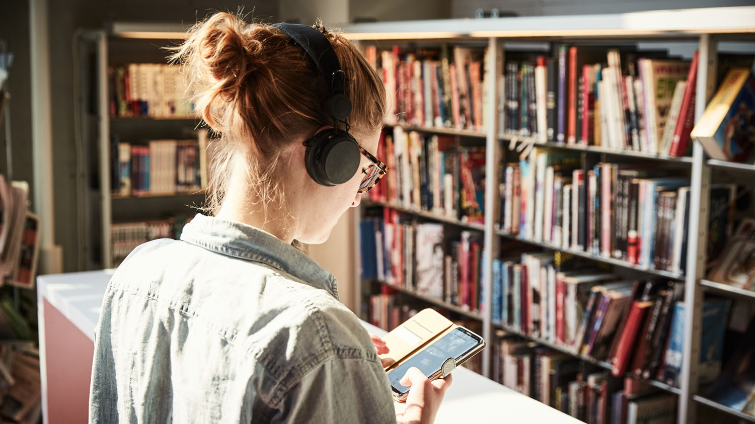 En person lyssnar på en ljudbok i ett bibliotek.
