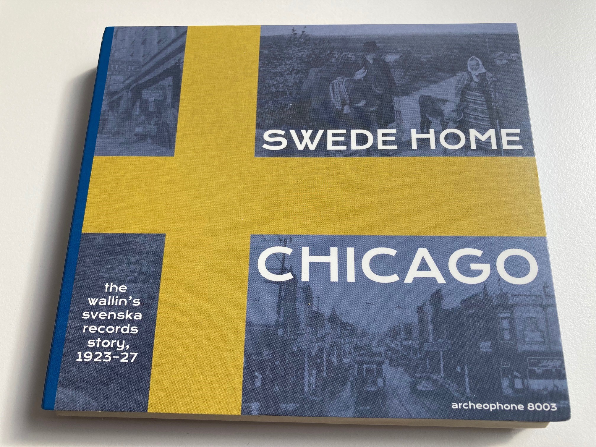 Omslag till CD-utgåvan Swede Home Chicago, med vit text på blå botten och ett gult kors som i svenska flaggan