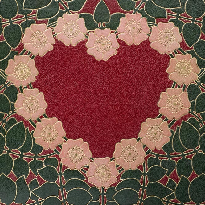 Foto av detalj av bokband med ett hjärta av rosa blommor i skinnmosaik.
