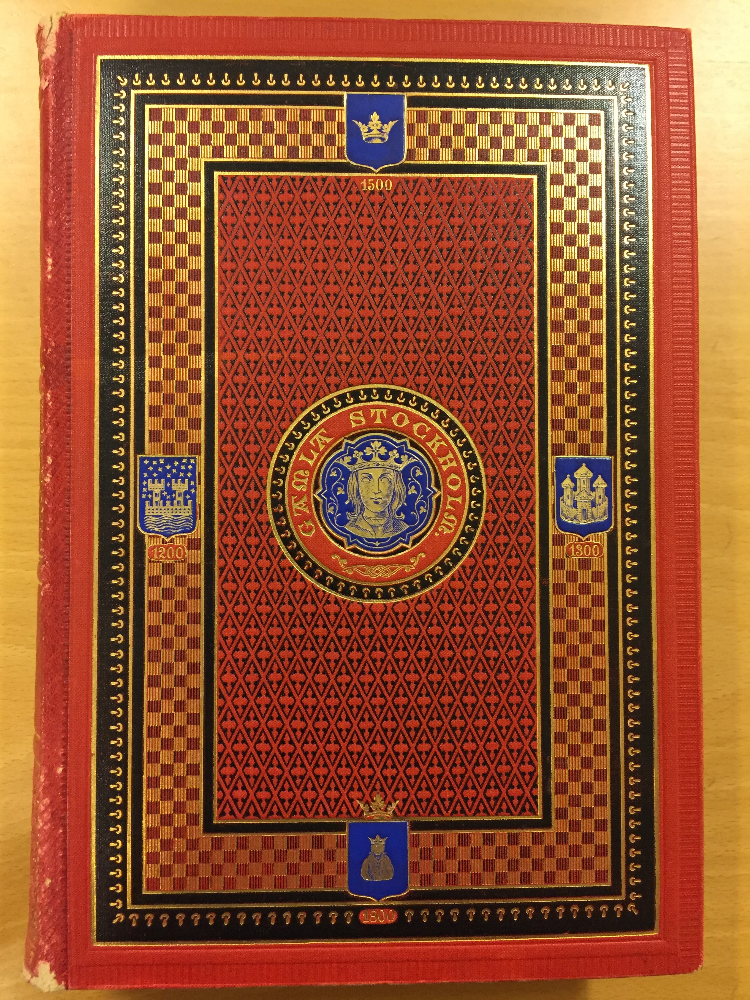 Bokomslag med rikt detaljerat mönster i rött, svart, blått och guld.