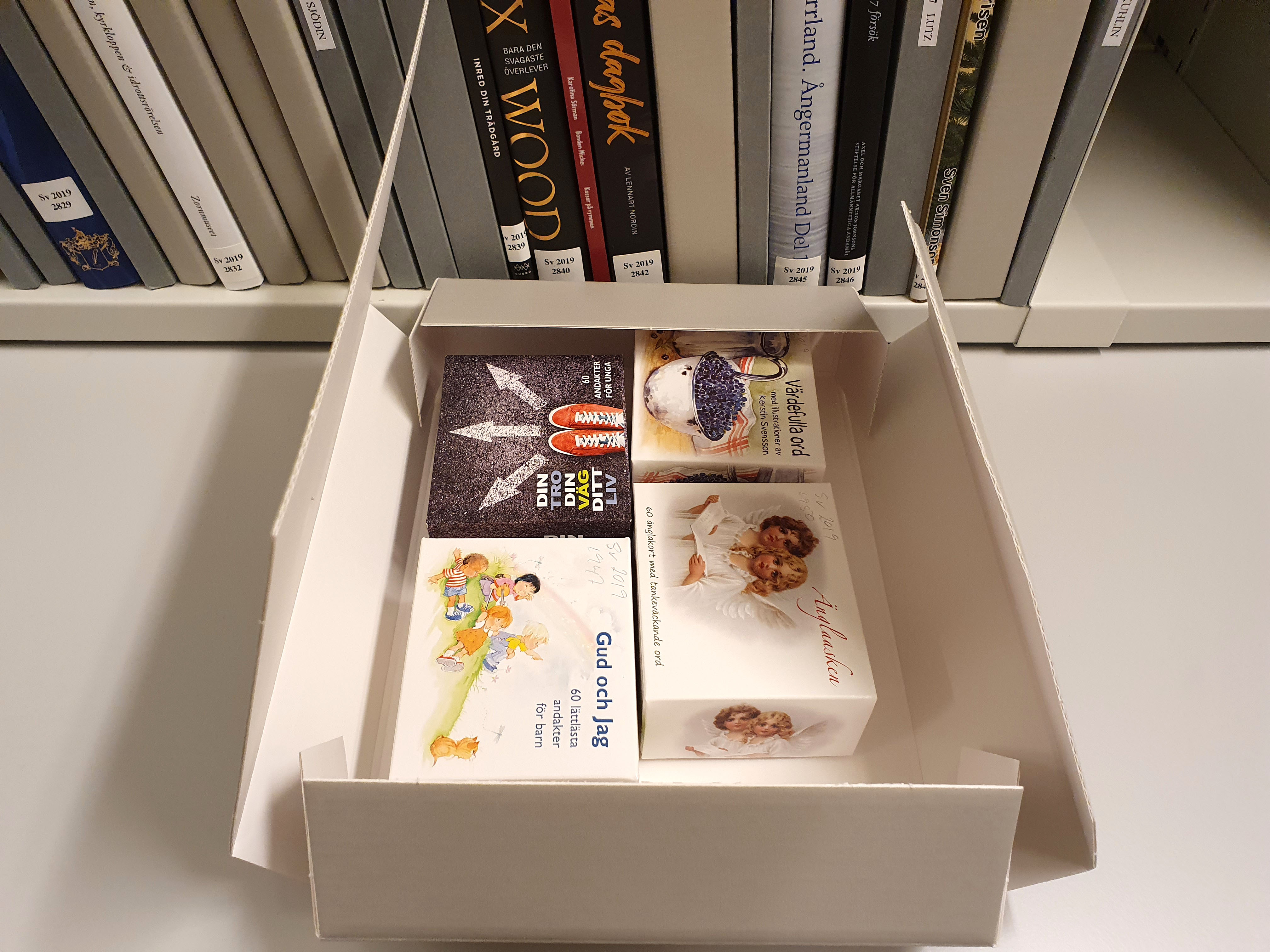 Fyra små böcker är placerade tillsammans i en arkivkapsel.