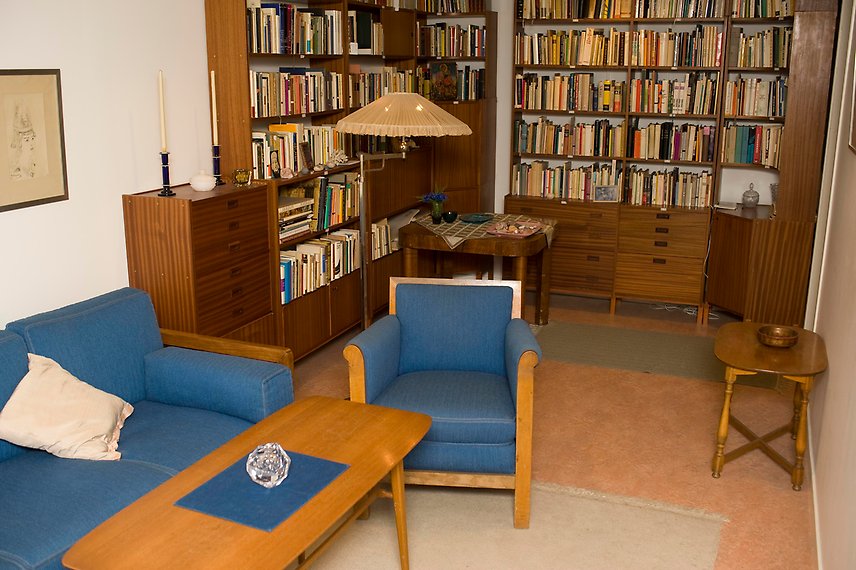 Ett rum med en blå soffa och blå fåtölj samt flera bokhyllor fyllda av böcker.