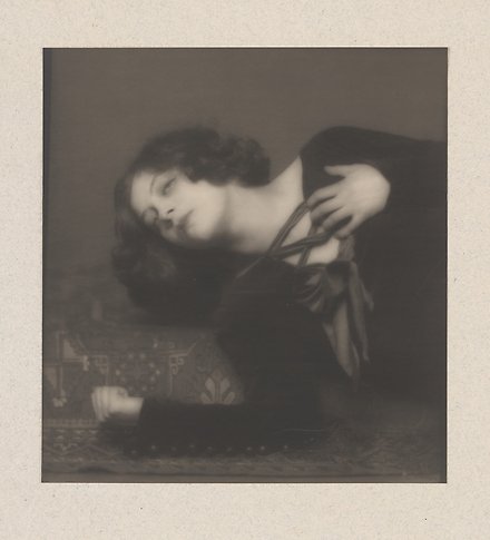 Svartvitt fotografi av en finklädd kvinna som ligger ner och ser dramatisk ut.