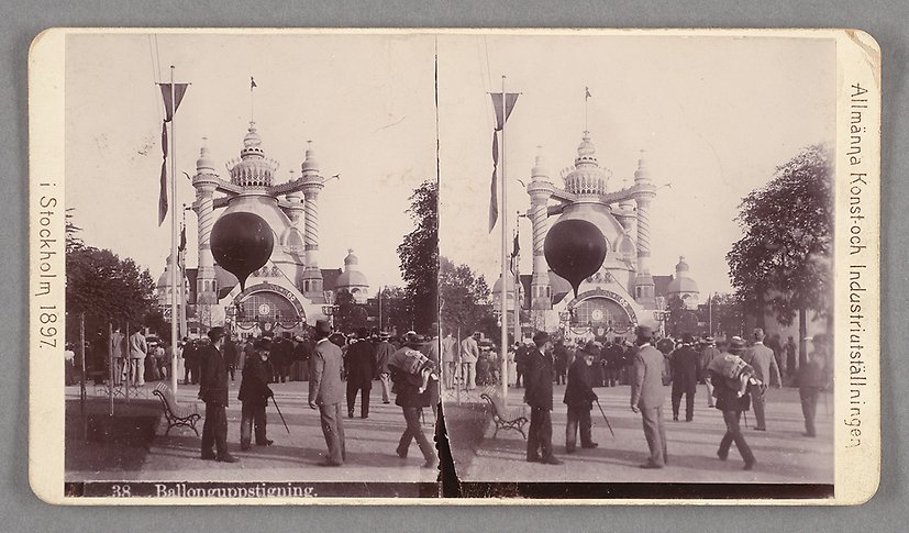 Svartvitt fotografi av en folksamling som tittar på en stor ballong framför ett litet konstnärligt byggt hus med fem små torn.
