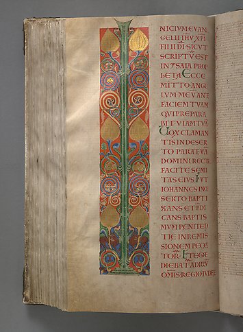 A book page with ornamentation in gold, green and red. 