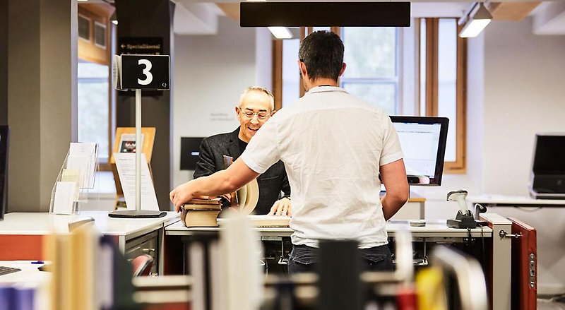 En bibliotekarie hjälper en man med ett lån av böcker.