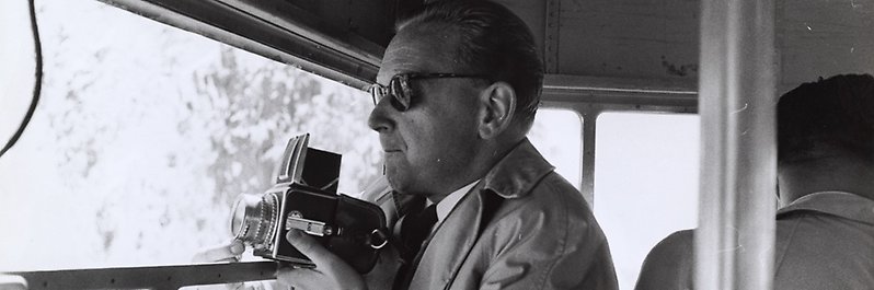 Svartvitt fotografi av Dag Hammarskjöld med en kamera.