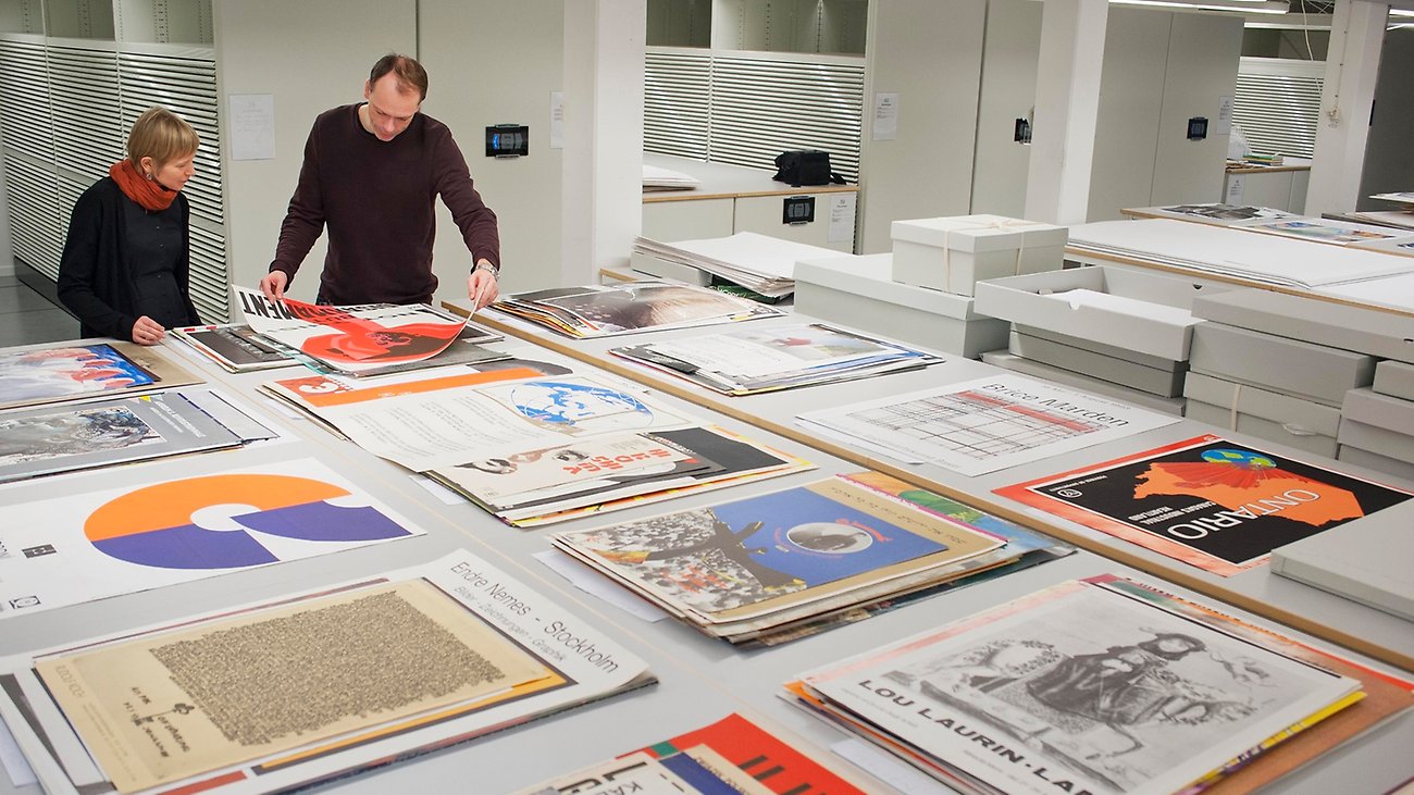 Two people sort and archive posters.