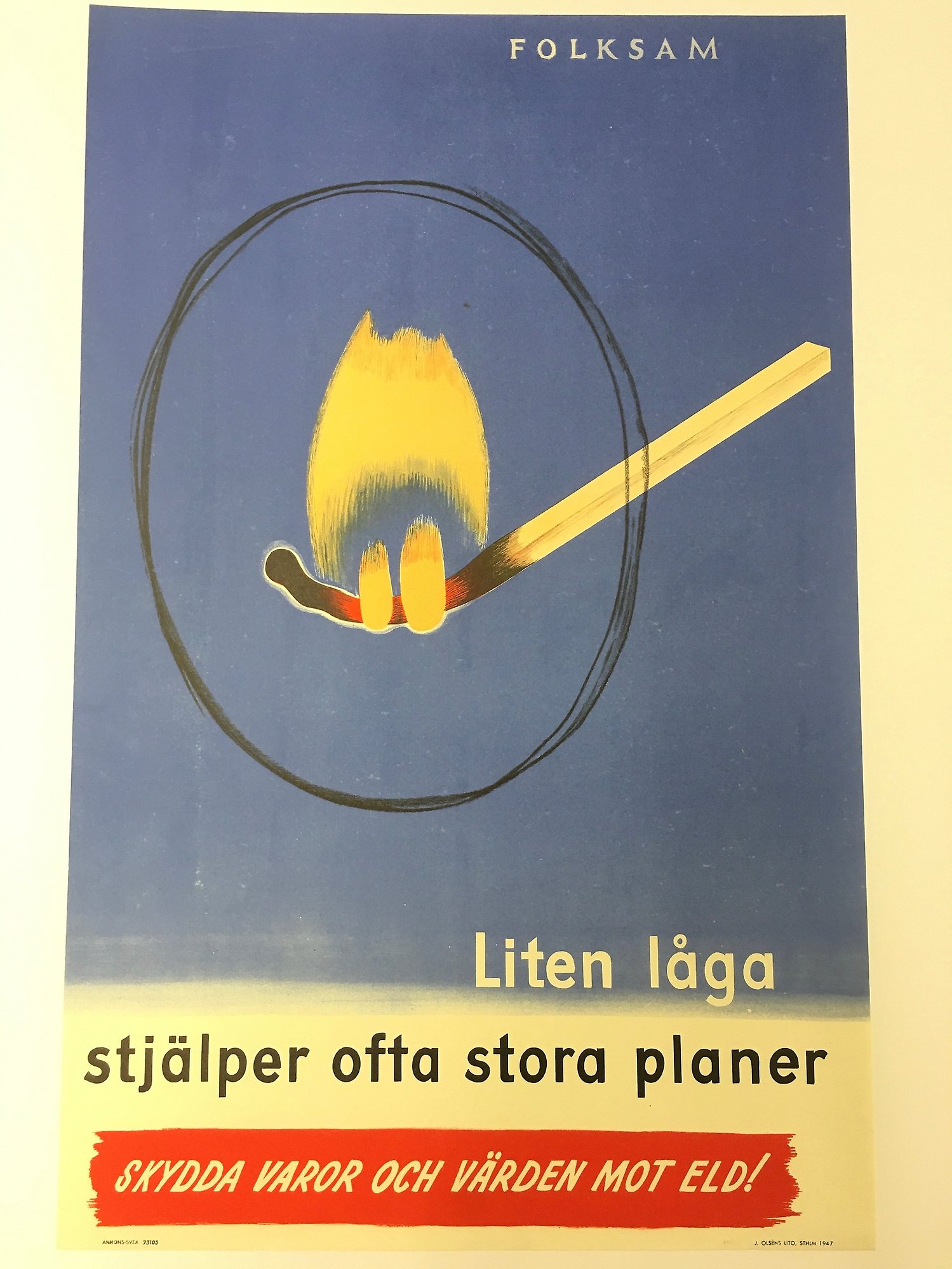 Tecknad affisch med en stor böjd tändsticka där elden är markerad med en cirkel. Texten lyder: Liten låga stjälper ofta stora planer. Skydda varor och värden mot eld! Folksam.