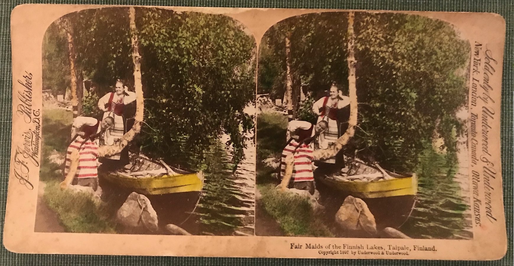 Två unga kvinnor iklädda folkdräkter poserar vid en båt vid en sjö nära Taipale i Finland.