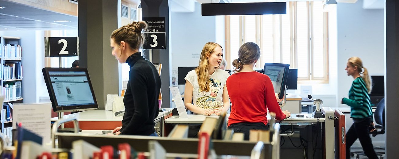 Personer vid datorer och med bokvagnar runtom.