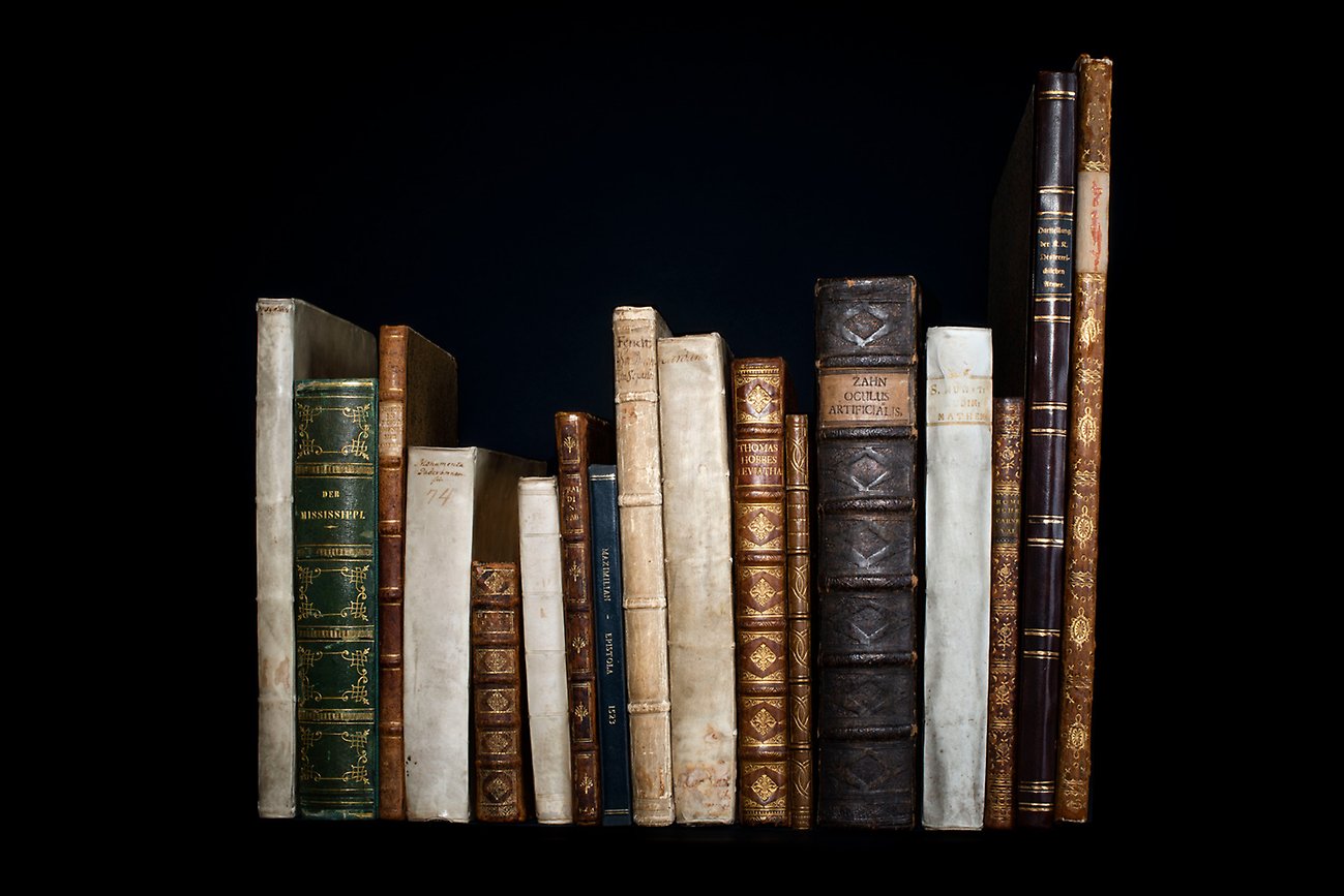 Older books lined up against a black background.