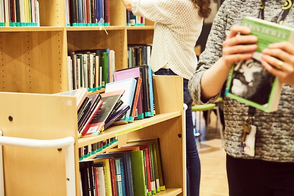 Två personer hämtar böcker med en bokvagn